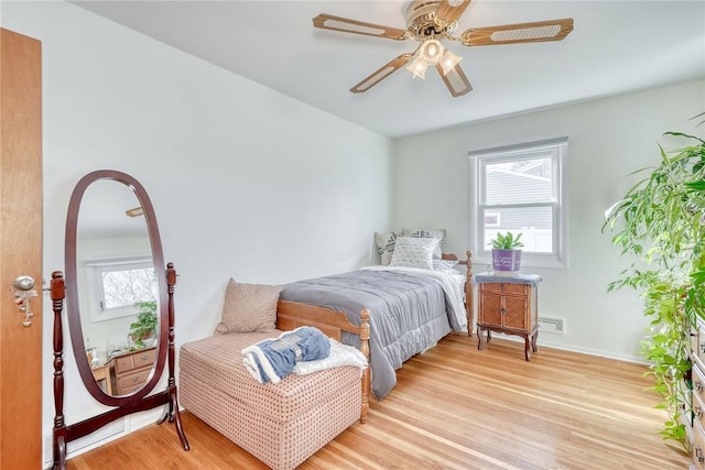 bedroom with baseboards, multiple windows, ceiling fan, and light wood finished floors