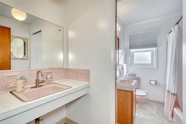 bathroom featuring backsplash, toilet, vanity, and baseboards