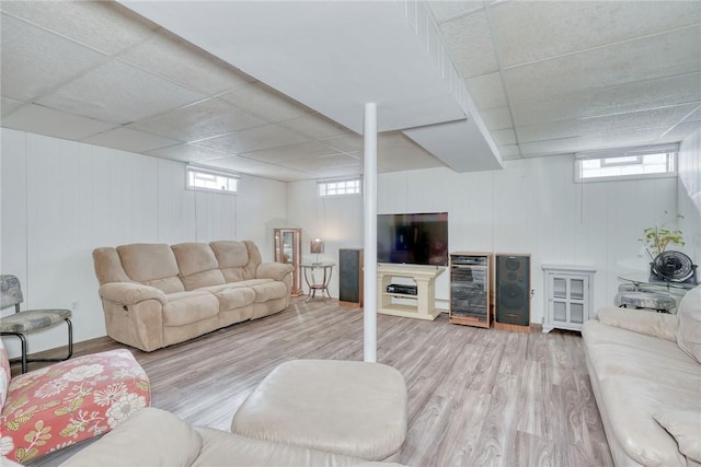 living area with a wealth of natural light, a drop ceiling, beverage cooler, and wood finished floors