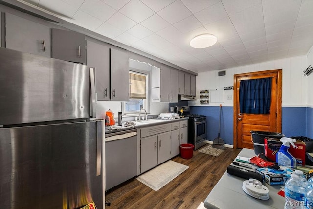 kitchen with gray cabinetry, dark wood-type flooring, light countertops, stainless steel appliances, and a sink