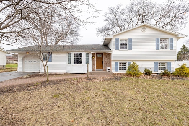 split level home with a garage, a front lawn, and driveway