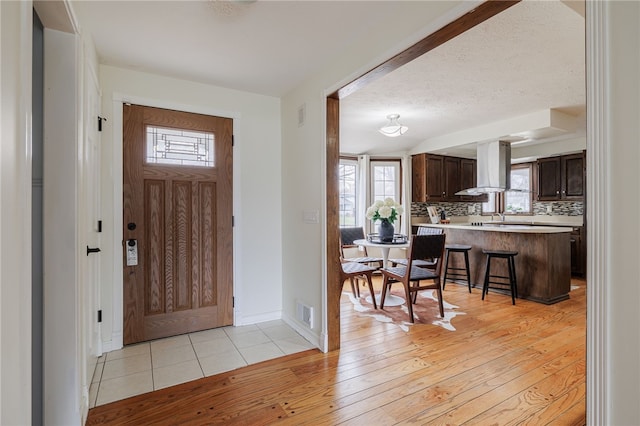 foyer entrance with light wood-type flooring, a healthy amount of sunlight, and visible vents