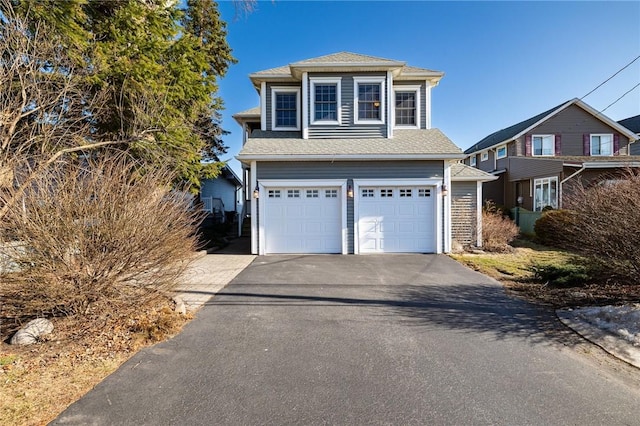 traditional-style home with aphalt driveway, an attached garage, and a shingled roof