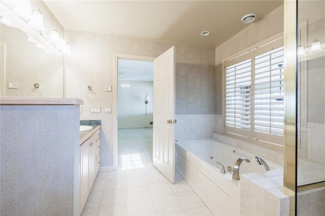 bathroom with a tub with jets, vanity, and tile patterned flooring