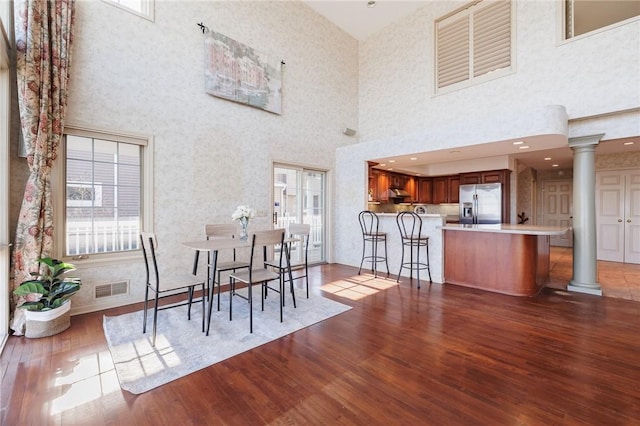 dining space featuring visible vents, ornate columns, and wood finished floors