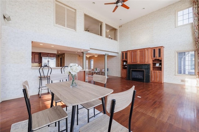 dining area featuring ornate columns, a healthy amount of sunlight, wood-type flooring, and a fireplace