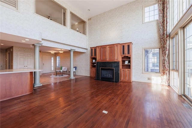 unfurnished living room with dark wood finished floors, decorative columns, a fireplace, and visible vents