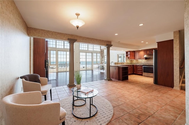 living area featuring decorative columns, recessed lighting, and light tile patterned floors