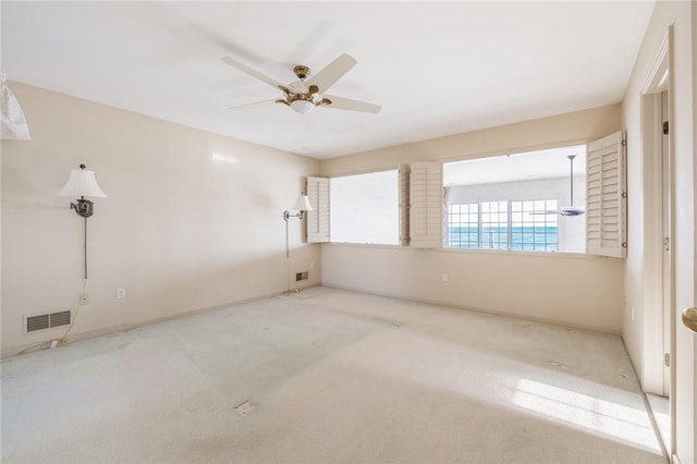 spare room featuring carpet flooring, visible vents, and ceiling fan