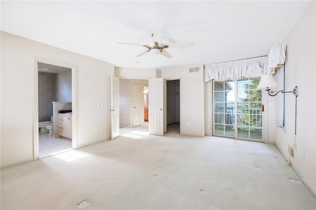 unfurnished bedroom with access to exterior, visible vents, a spacious closet, light colored carpet, and ensuite bath