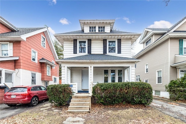 american foursquare style home featuring covered porch and roof with shingles