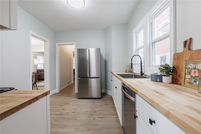 kitchen with white cabinetry, appliances with stainless steel finishes, wooden counters, and a sink