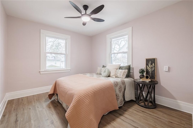 bedroom featuring wood finished floors, baseboards, and ceiling fan