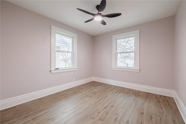 spare room with wood finished floors, a healthy amount of sunlight, baseboards, and ceiling fan