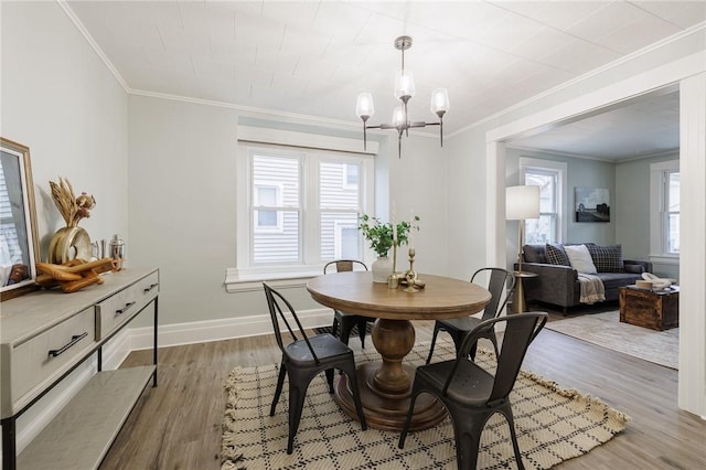 dining area with crown molding, wood finished floors, baseboards, and a chandelier