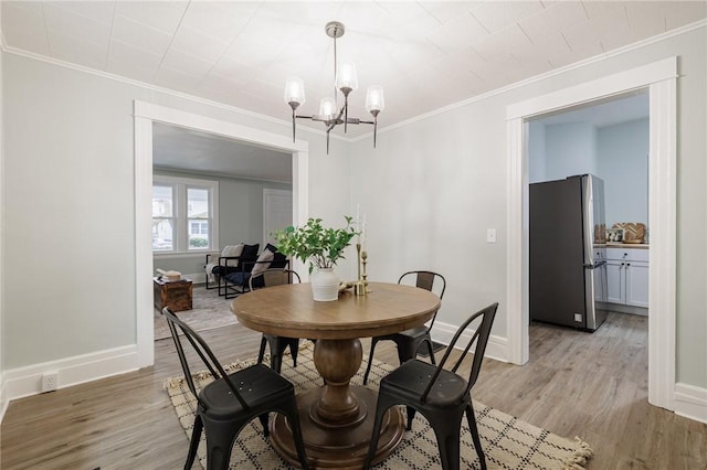 dining area featuring a chandelier, baseboards, light wood-style floors, and ornamental molding