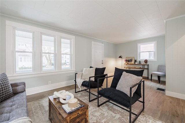 living room with visible vents, baseboards, light wood-style flooring, and ornamental molding