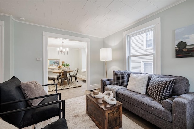 living area featuring a chandelier, ornamental molding, baseboards, and wood finished floors