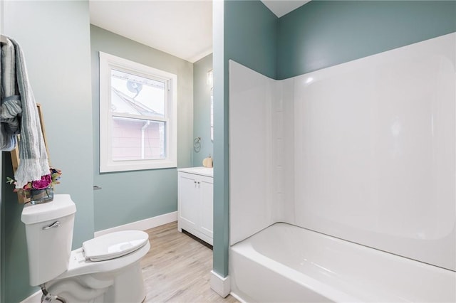 bathroom with vanity, wood finished floors, baseboards, bathtub / shower combination, and toilet