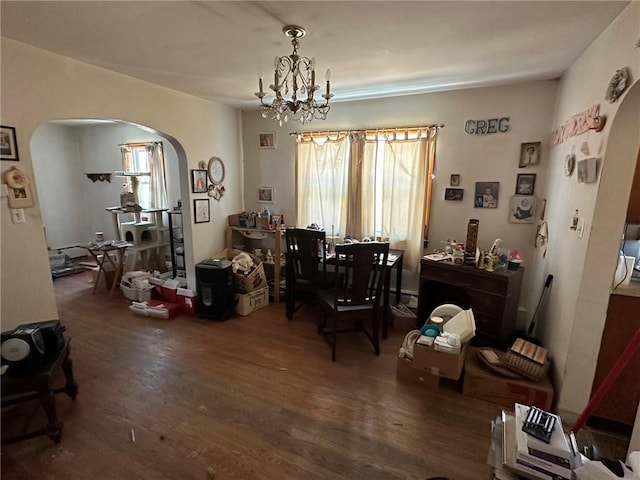 dining room featuring a chandelier, arched walkways, and wood finished floors