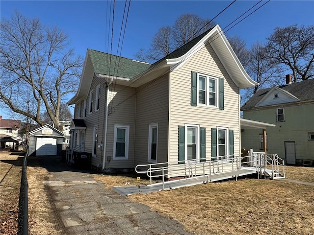 view of side of home featuring a garage, covered porch, an outdoor structure, and driveway