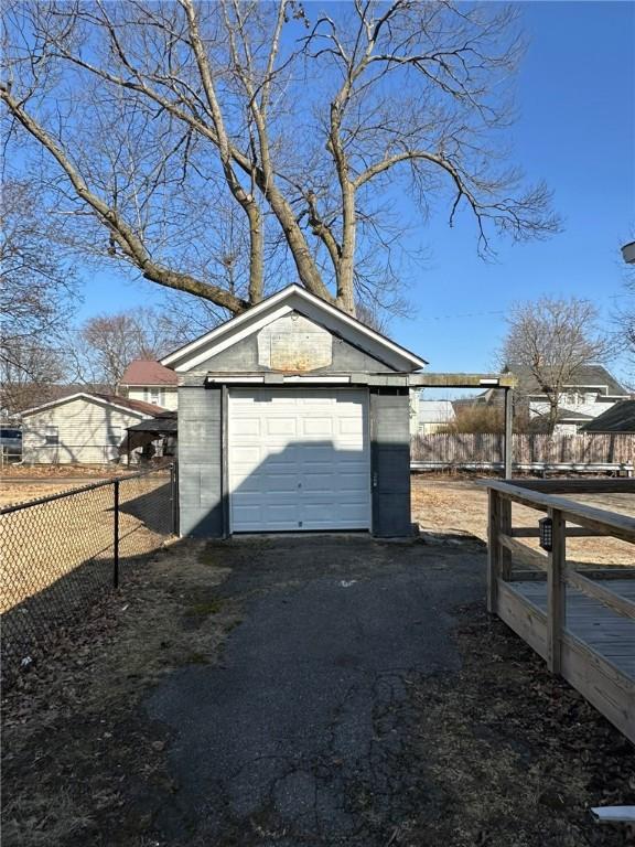 detached garage featuring driveway and fence