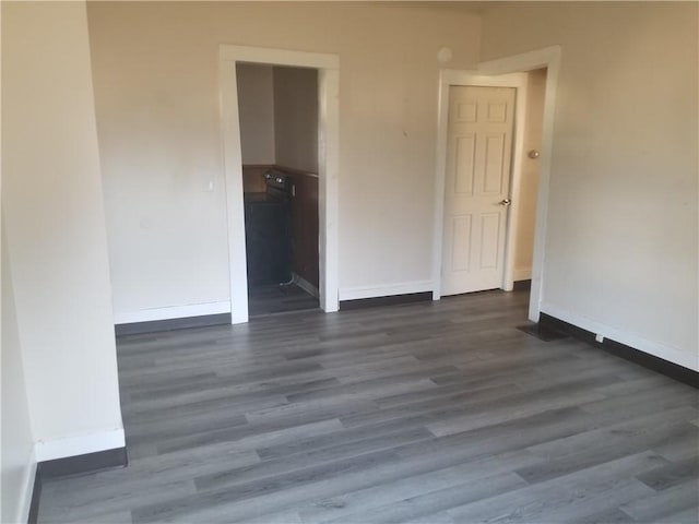 empty room featuring dark wood-style floors and baseboards