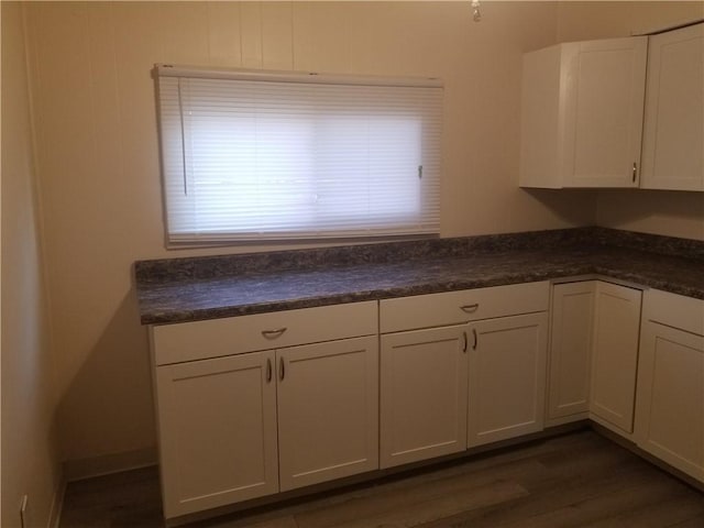 kitchen with dark countertops, dark wood finished floors, and white cabinetry