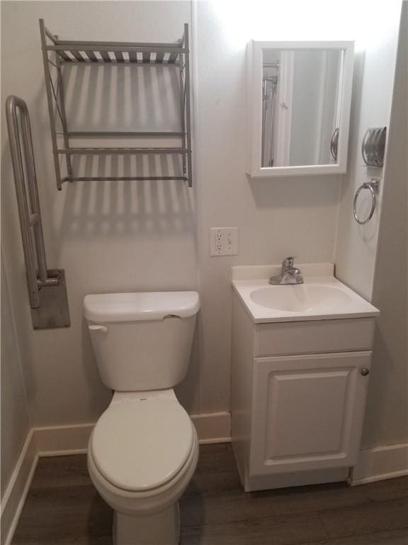 bathroom with vanity, toilet, wood finished floors, and baseboards