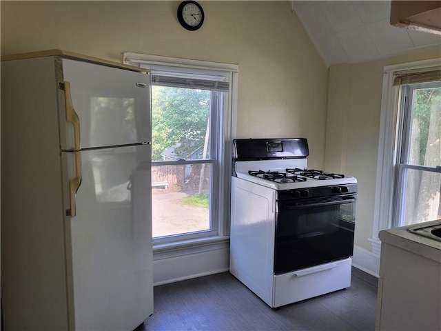 kitchen with a healthy amount of sunlight, vaulted ceiling, gas range oven, and freestanding refrigerator