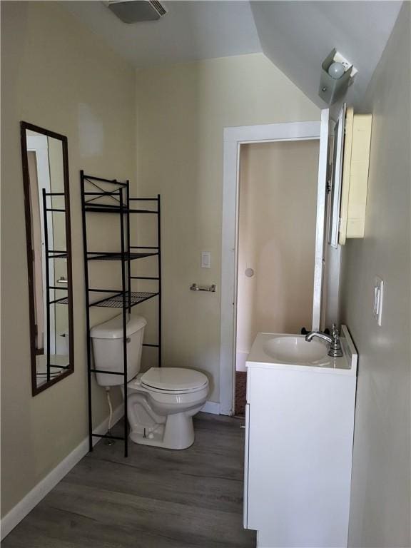 half bath with vanity, toilet, wood finished floors, and baseboards