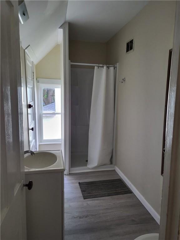 bathroom featuring visible vents, a shower stall, baseboards, wood finished floors, and vanity