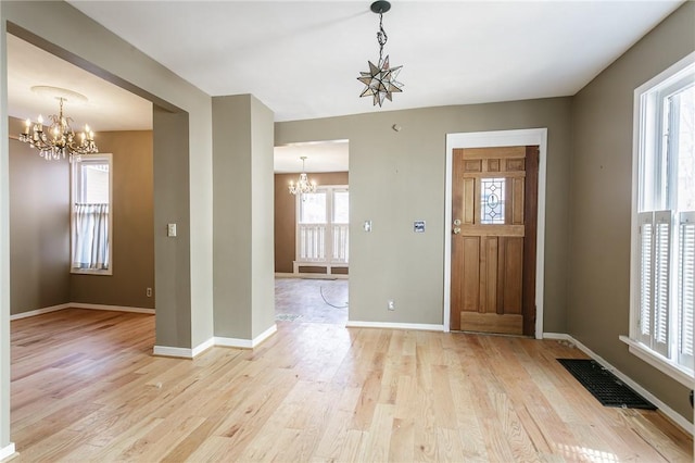 entryway featuring visible vents, baseboards, a chandelier, and light wood-style flooring