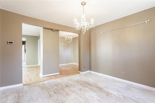 empty room featuring a notable chandelier, wood finished floors, and baseboards