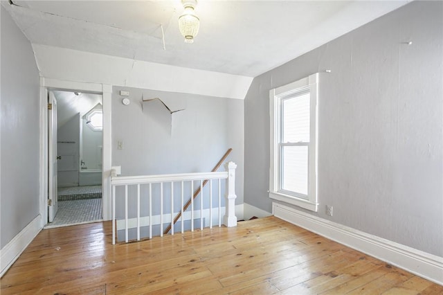 additional living space featuring baseboards, lofted ceiling, and hardwood / wood-style flooring