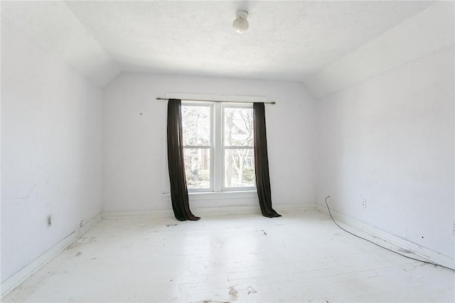 empty room with lofted ceiling and a textured ceiling