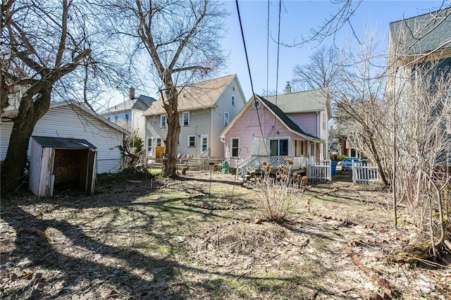 rear view of property featuring an outdoor structure and a shed