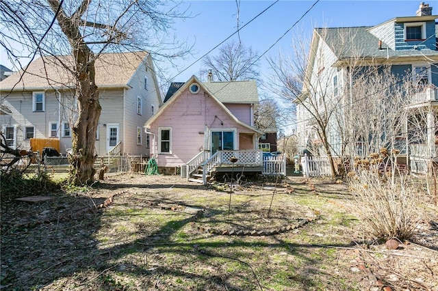 back of property with a wooden deck and fence