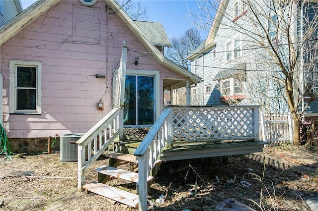 rear view of property with central air condition unit, a wooden deck, and a shingled roof