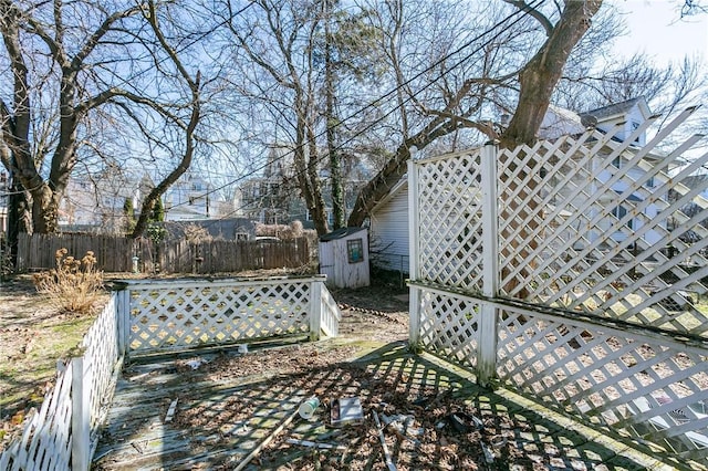 view of yard featuring a storage shed, an outbuilding, and fence