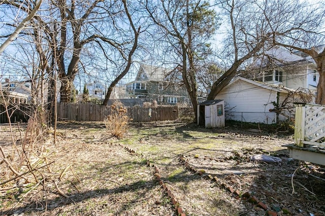 view of yard featuring a storage shed, an outbuilding, and fence