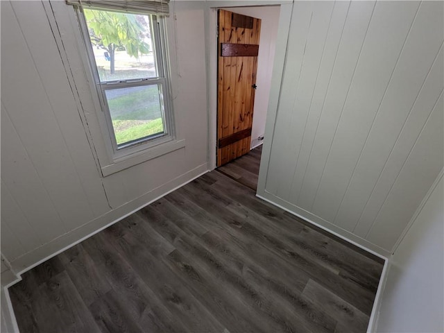 unfurnished room with baseboards and dark wood-style floors