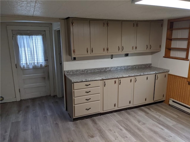 kitchen featuring a wainscoted wall, a baseboard radiator, light countertops, light wood-style floors, and wood walls