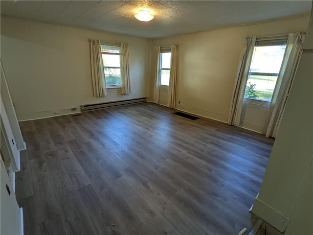 empty room featuring a baseboard heating unit, visible vents, and dark wood-style flooring