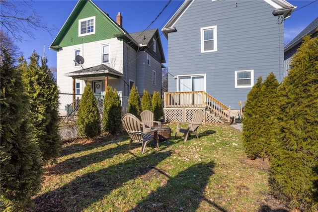 rear view of property featuring a yard, a chimney, and an outdoor fire pit