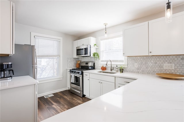 kitchen featuring plenty of natural light, appliances with stainless steel finishes, white cabinetry, and a sink