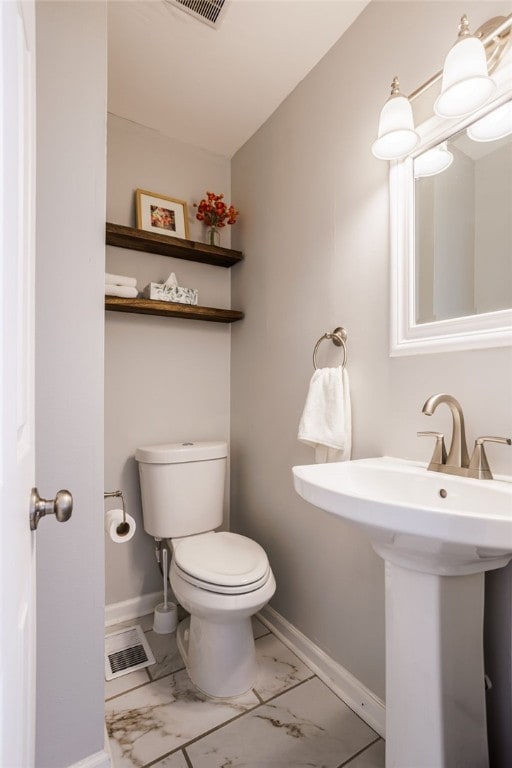 half bathroom with visible vents, toilet, baseboards, and marble finish floor