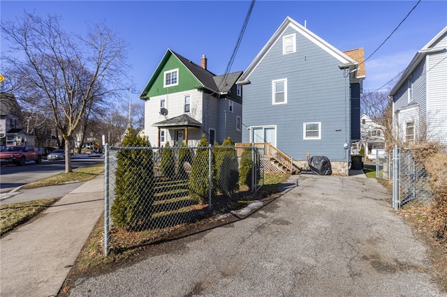 rear view of property featuring a gate and fence