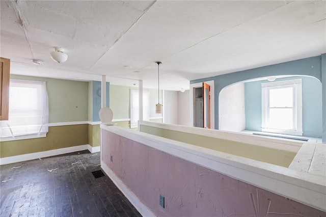 hallway with visible vents, plenty of natural light, baseboards, and dark wood-style flooring