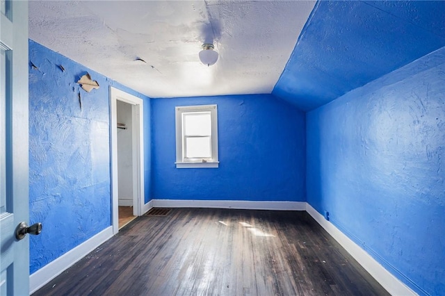 bonus room featuring a textured ceiling, baseboards, and wood finished floors